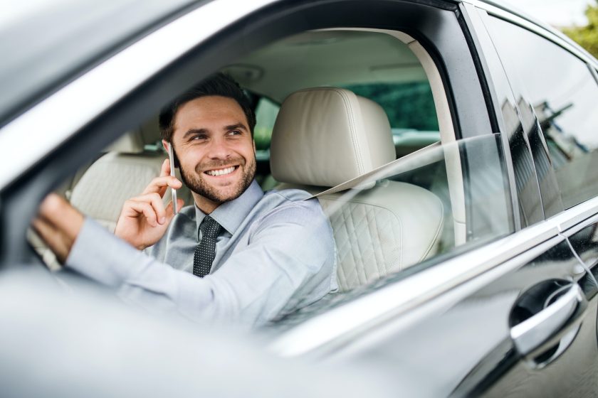 Young businessman with shirt, tie and smartphone sitting in car